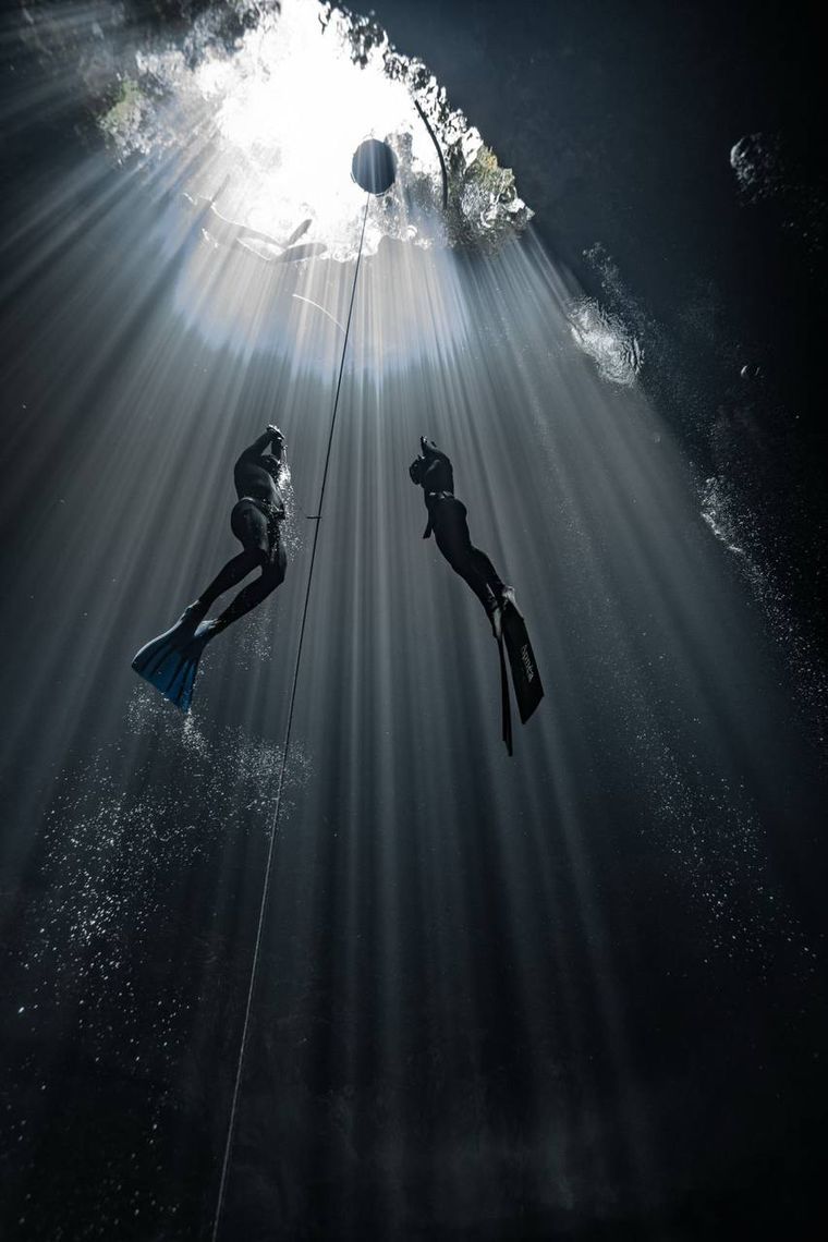 Silhouettes on the line under a cenote opening